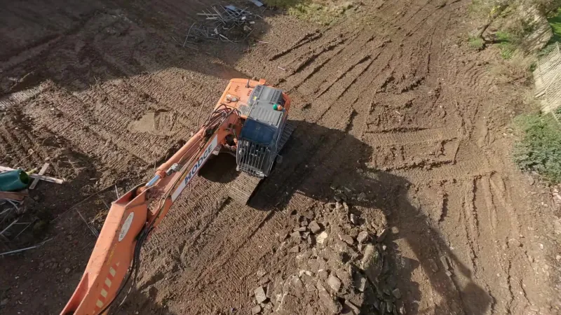 Overhead drone view of a Hodge excavator on a cleared site of tracked earth